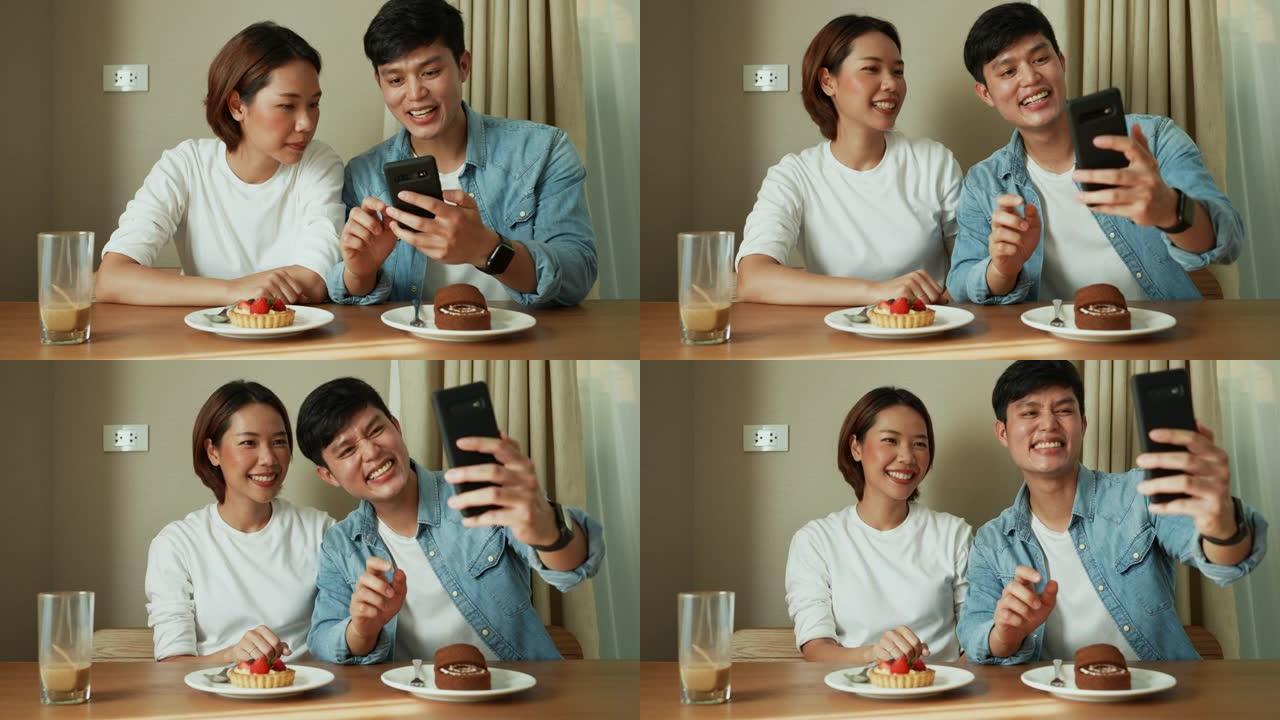 一群亚洲恋人坐在饭厅里与幸福交谈，并使用智能手机拍照并在社交媒体上上传慢动作场景度假概念中的生活方式