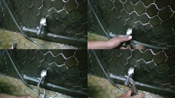 修理工使用可调扳手将马桶软管连接到墙上的截止阀并拧紧