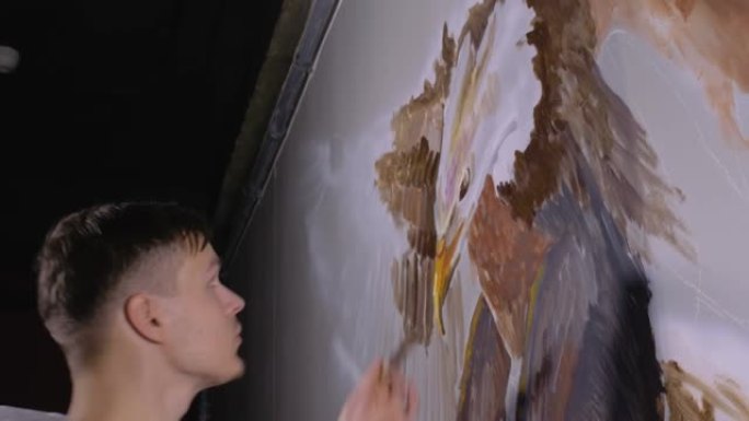艺术家设计师在墙上画了一只鹰。工匠装饰师用丙烯酸油色画一幅画，看着手机里的草图。