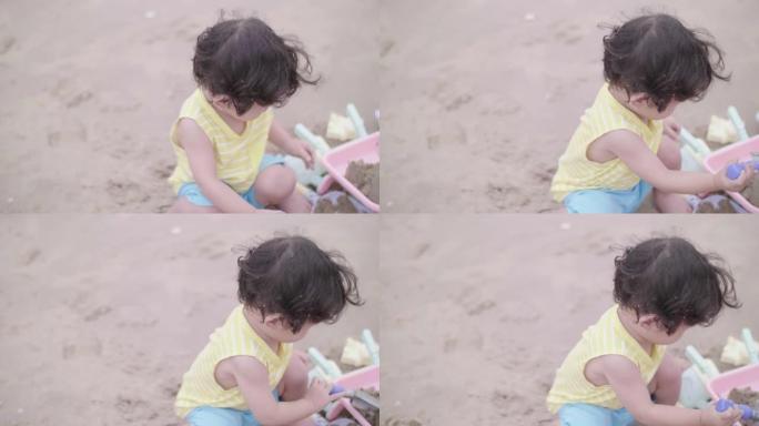 小男孩在沙滩上玩沙子和快乐。