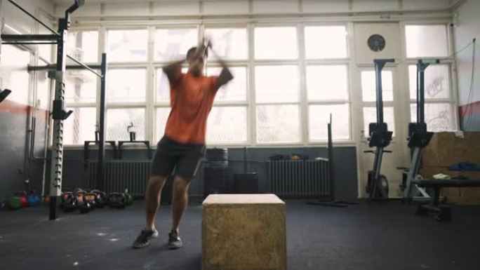 高加索运动型男子在健身房的盒子上跳跃