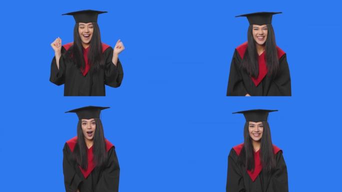 穿着毕业服装的女学生的肖像看着相机，令人赞叹不已。年轻的黑发女人在工作室摆姿势，蓝色屏幕背景。特写。
