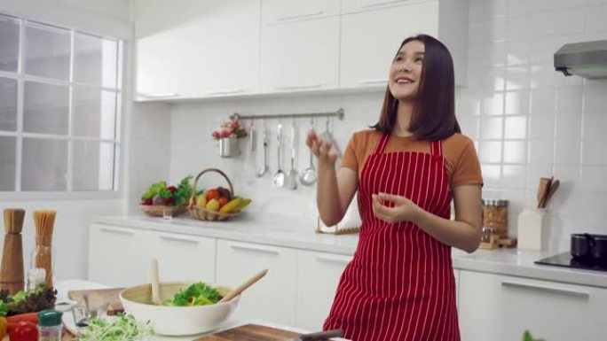 亚洲女性在家里的厨房里烹饪和学习数字平板电脑
