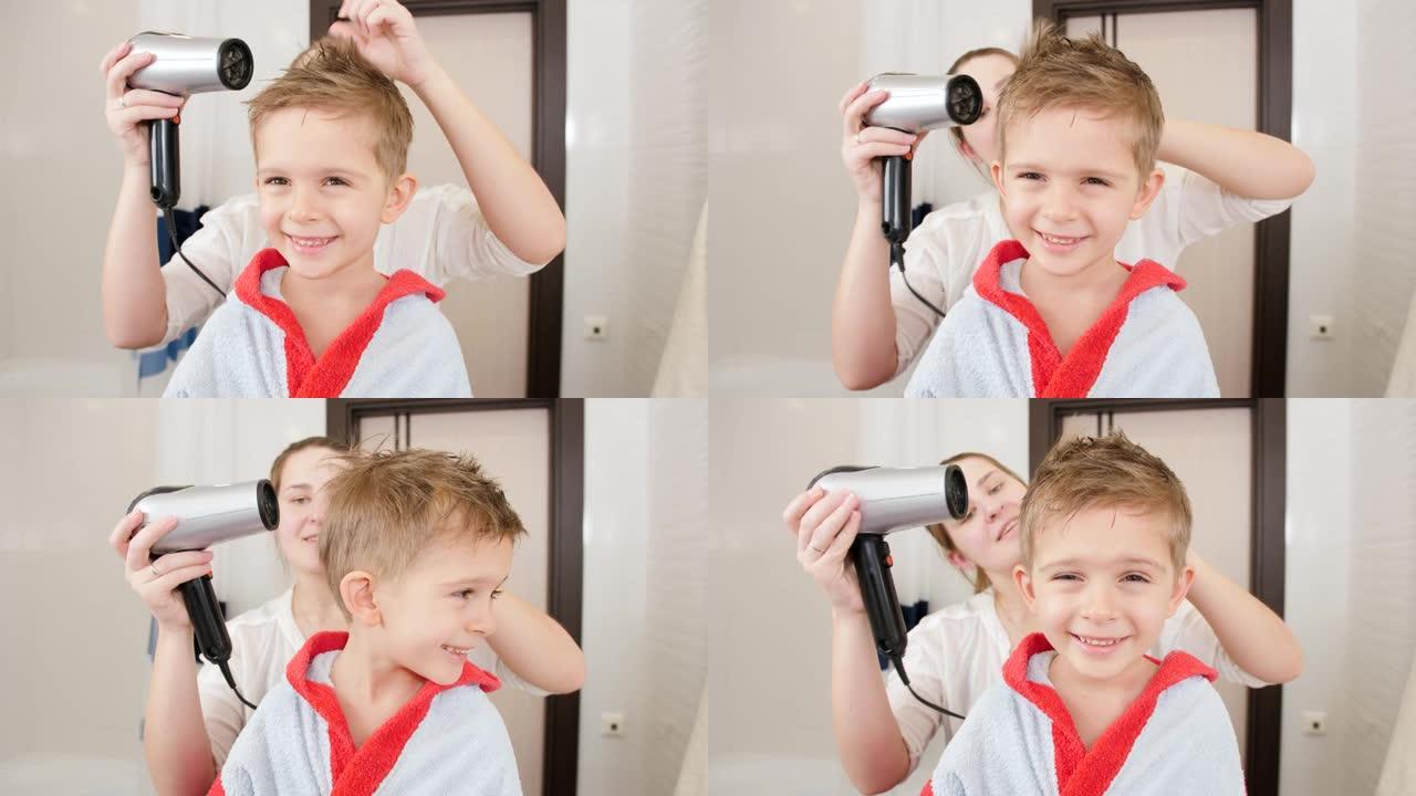 快乐微笑的小男孩在洗澡时看着镜子，母亲用吹风机吹干头发。儿童卫生和家庭保健的概念。家里有爱心的父母和