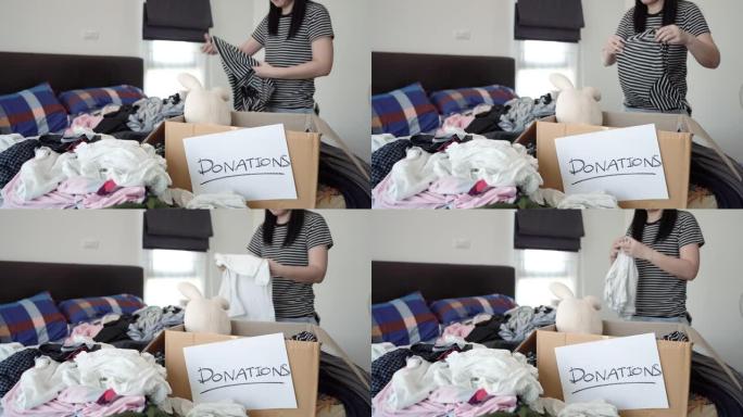 亚洲妇女在捐赠箱中打包衣服。