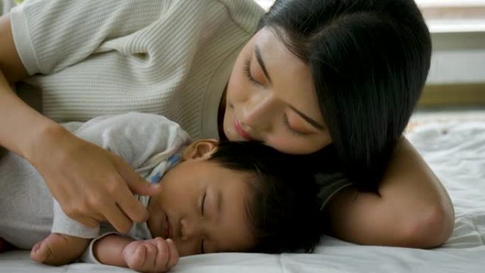 年轻的亚洲妈妈在家照顾新生儿。