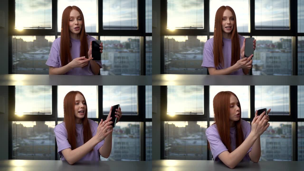 微笑的年轻女性博客的网络摄像头视图在窗口背景上的视频聊天期间问候追随者并谈论电话。