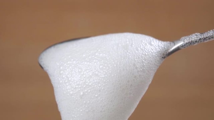 浓稠的牛奶泡沫从一茶匙中掉落