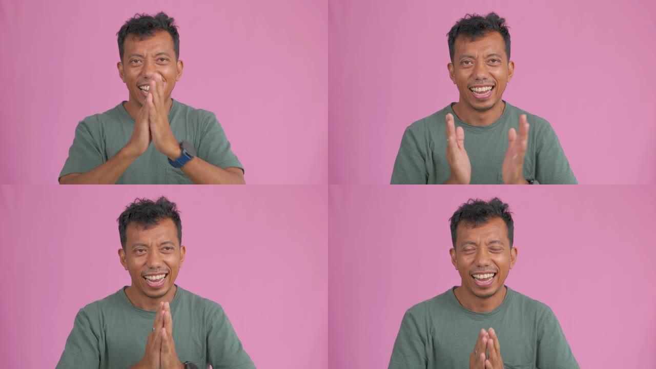 电影工作室拍摄的亚洲男子微笑欢呼的情绪做出了非常快乐的表情，赢得了感觉，令人兴奋，带有粉红色的背景。