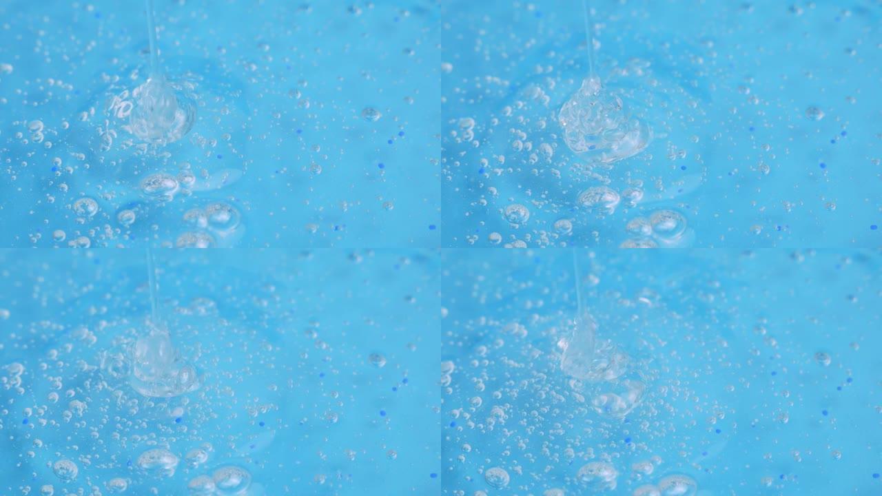 一小撮带有微小气泡的透明化妆品凝胶滴落在蓝色表面上。面部精华液，抗衰老霜，洗发水，抗菌凝胶，透明质酸
