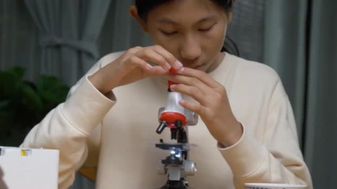 亚洲女孩利用显微镜在夜间在家，教育生活方式的理念。