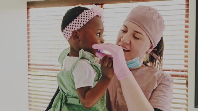 一名年轻牙医刷牙可爱的小女孩牙齿的4k视频片段