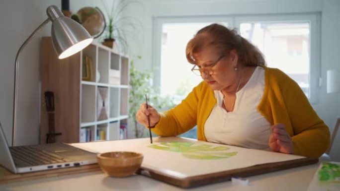 一位资深女士在家中在线上水彩画课