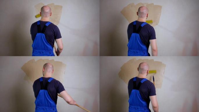 男性房屋画家在公寓的墙壁上使用带有滚轮的墙纸胶