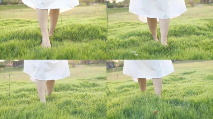 镜头在脚前慢动作，女人不穿鞋，走在柔软的绿色草地上。