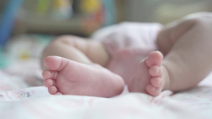 关闭婴儿婴儿小脚在靠近窗户的床上移动。新生儿床上的脚印，婴儿脚的细节。