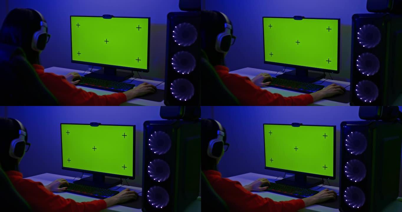 一台功能强大的个人电脑的绿屏，一名女性玩家正坐在电脑前。强大的个人电脑，适合家庭电脑游戏迷。后视图。