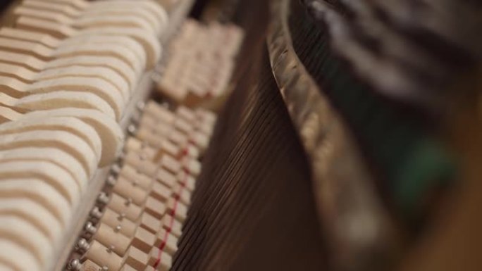 从钢琴锤的内部观看，特写。钢琴锤子敲打琴弦的机制