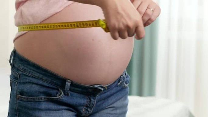 孕妇用黄色卷尺检查尺寸的特写镜头。怀孕保健和节食的概念