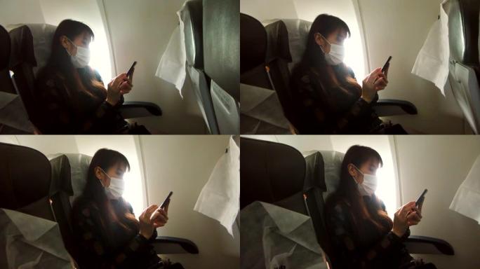 戴口罩的亚洲女性在飞机座椅上使用手机
