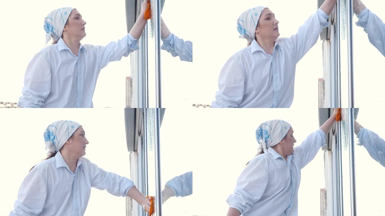 围着围巾的女人的侧视图用抹布洗窗户