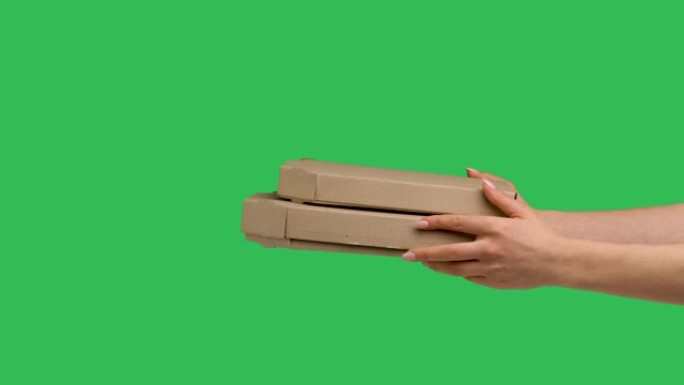 女性双手给两个纸板箱，上面有绿屏色度键的背景。晚餐时关闭带小吃的盒子。食品的快速快递。比萨店的广告。