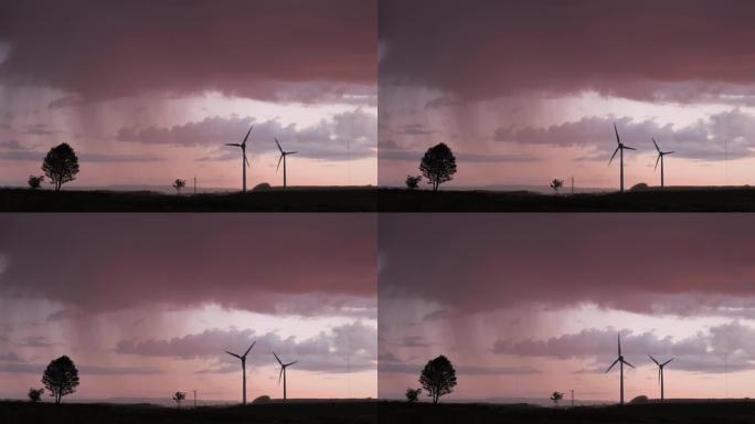 在日落雨云背景下的野外风力涡轮机
