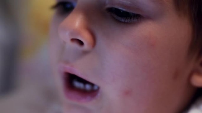 特写4k视频，小蹒跚学步的男孩揉眼睛，晚上感到疲倦。平板电脑屏幕在孩子的眼睛中反射