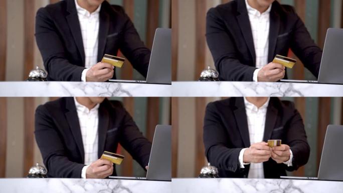 手持信用卡并在笔记本电脑键盘上打字的人的近距离工作预订，以预订付款或在互联网上在线购买电子商务购物或