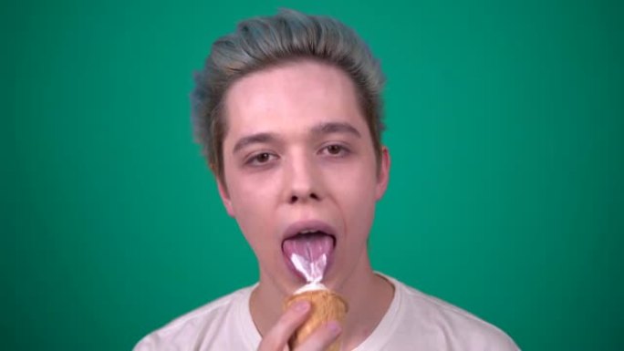 蓝色头发的年轻快乐男人在华夫饼杯里吃冰淇淋看着相机
