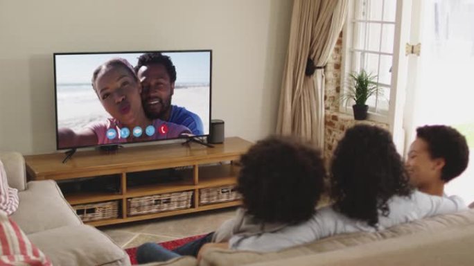 非裔美国人家庭坐在沙发上与电视屏幕上的朋友进行视频通话