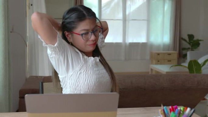 年轻的亚洲妇女在检疫从Covid 19大流行中新的正常生活方式时，正在电脑笔记本电脑上打字并伸展身体