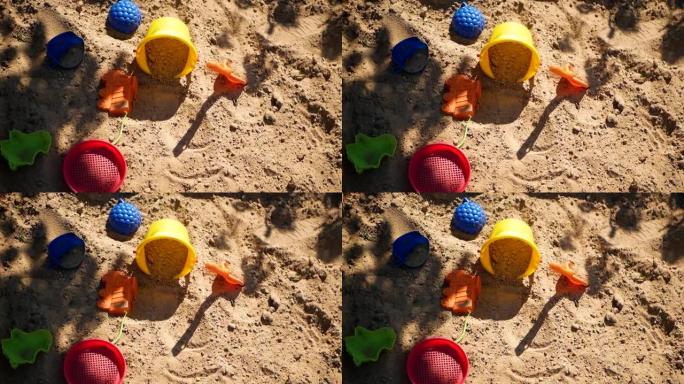 被遗弃在沙子里的塑料儿童玩具。沙子上植物的移动阴影