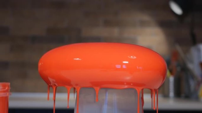 多莉视频。新鲜慕斯蛋糕上的红色糖霜滴。糕点师傅用红镜糖霜把蛋糕装满。特写