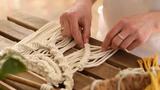 在家庭作坊中，妇女的双手在编织花边。手工制作的概念。