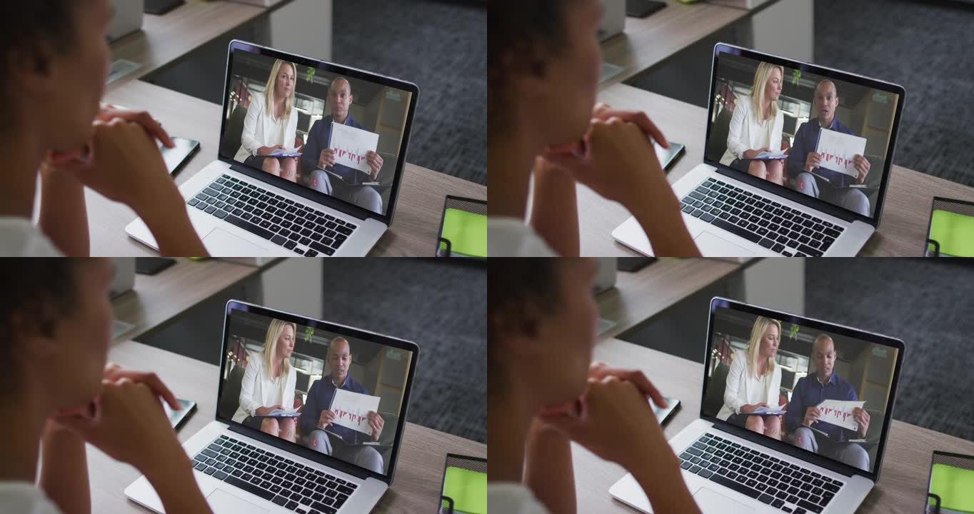 非裔美国女商人坐在办公桌前，使用笔记本电脑与同事进行视频通话