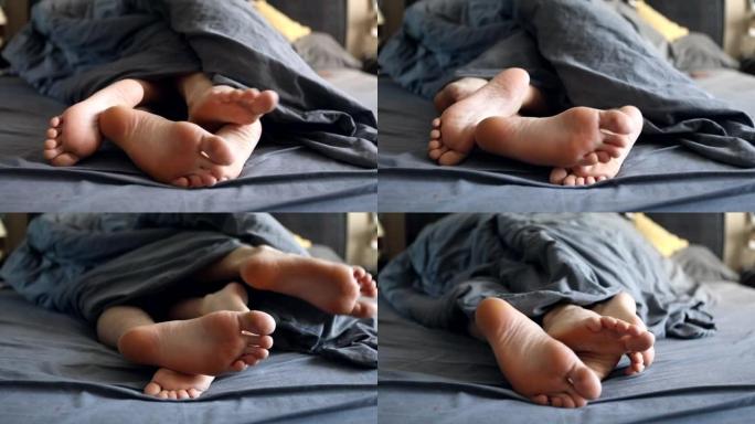 夫妻腿女人和男人在床上的灰色毯子下