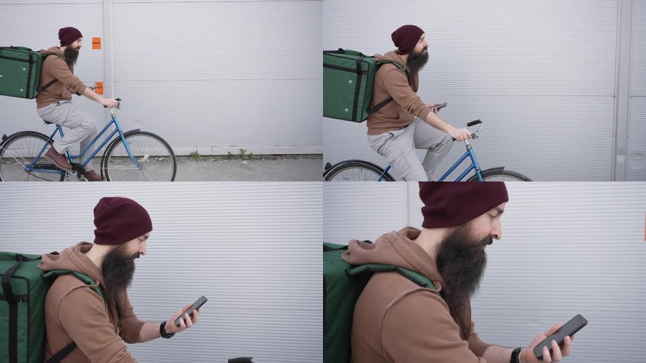 专用的男性送货员，在他的送货路线上，骑自行车，试图在手机上的gps应用程序上定位，以便找到正确的客户