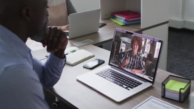 非裔美国高级男子在办公室的笔记本电脑上与男同事进行视频通话