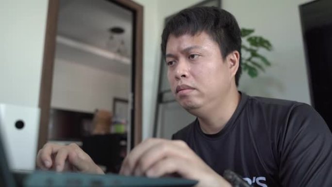 亚洲男子在家里用笔记本电脑上网。