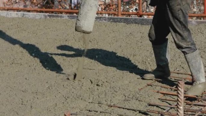 工程师将混凝土钢筋浇注到地板金属结构底座低角度中。用湿水泥浇筑地板的工人。穿着胶靴的建筑商与固井机一