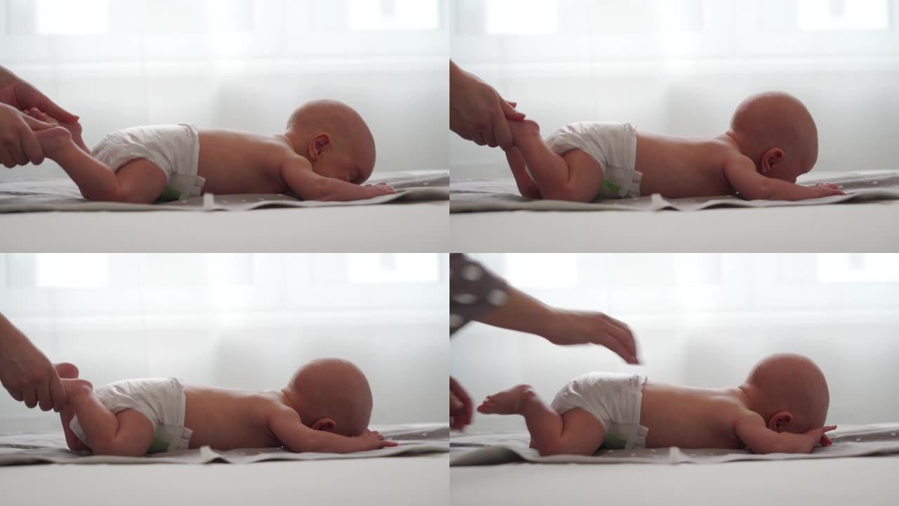 母亲与男婴做运动简单的运动，使婴儿的骨骼和肌肉更强壮，新生婴儿躺在床上的肚子上