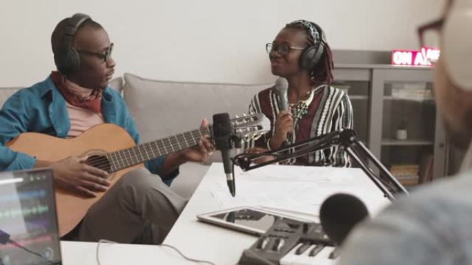两名音乐家在广播节目中弹吉他和唱歌