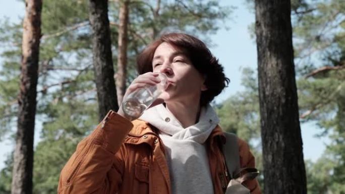 成熟的女人在森林里喝水