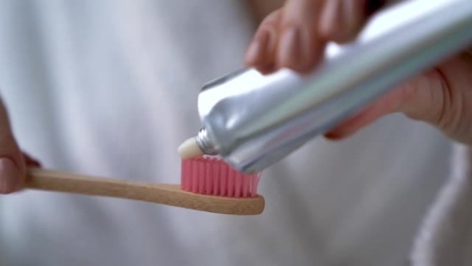女人在竹刷上挤牙膏。