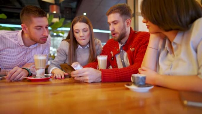 开朗的同事在餐厅喝咖啡并使用智能手机