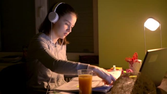 戴着耳机的少女在家中使用笔记本电脑