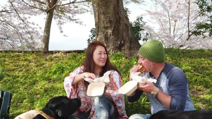 慢动作夫妇带着狗在樱花树下吃汉堡