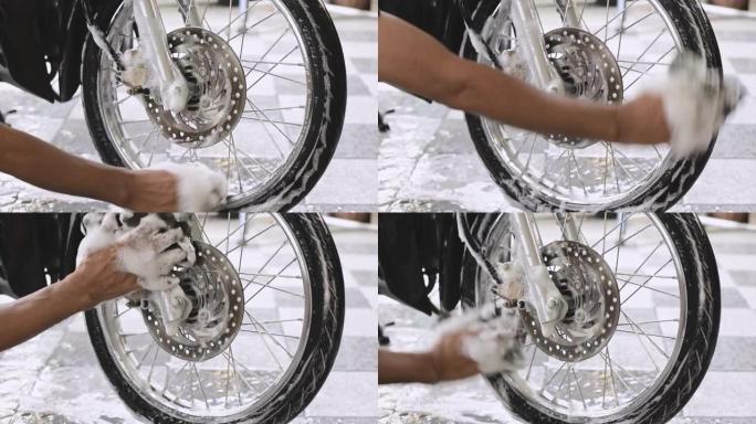 一个男人洗手摩托车前轮的特写镜头。