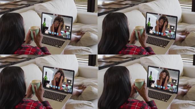 混血女人坐在沙发上，用笔记本电脑与女性朋友进行视频通话